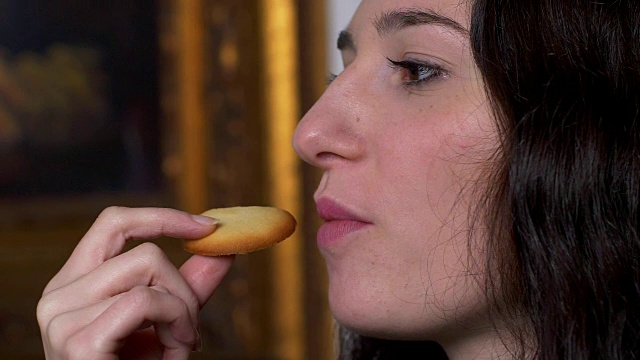 年轻漂亮的女人在吃美味的饼干，慢镜头视频素材