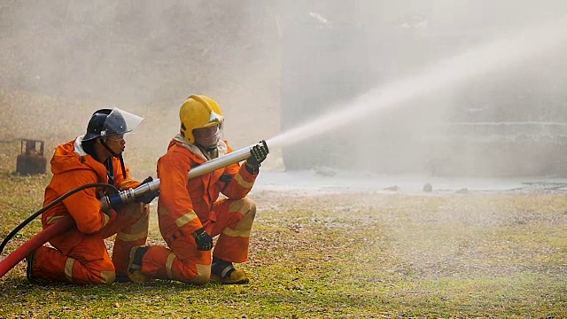 消防队员在一次灭火行动中，用高压喷嘴将泡沫喷向发生火灾的卡车视频素材
