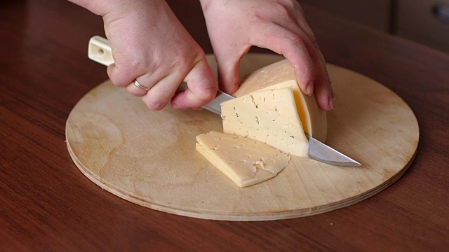 女孩切奶酪的特写在圆切板上视频素材
