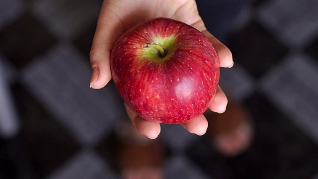 一个女孩的特写，拿着一个红色多汁的成熟苹果。视频素材