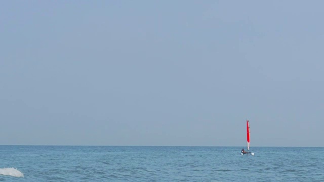 一艘在海上挂着红帆的帆船视频素材