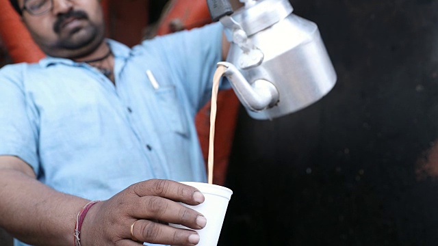 印度德里的一个市场摊位上，男茶商正在往杯子里倒茶视频素材