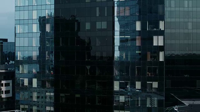 无人机拍摄的从外面进入办公大楼的商人工作和看着窗外。美丽的飞行缩小拍摄的金融区摩天大楼。视频素材