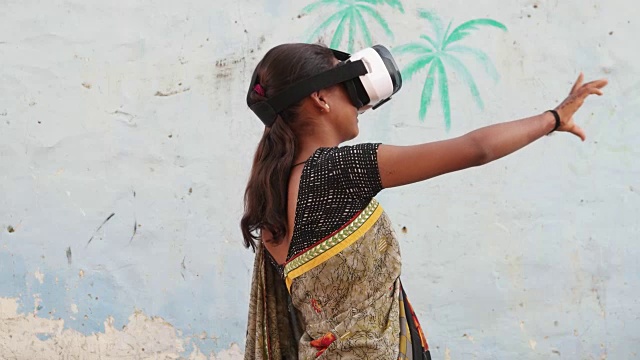 年轻的少女戴着VR虚拟现实头盔工作游戏享受音乐玩参与电影电影手点前沿当代无线通信技术超现实的印度农村视频素材