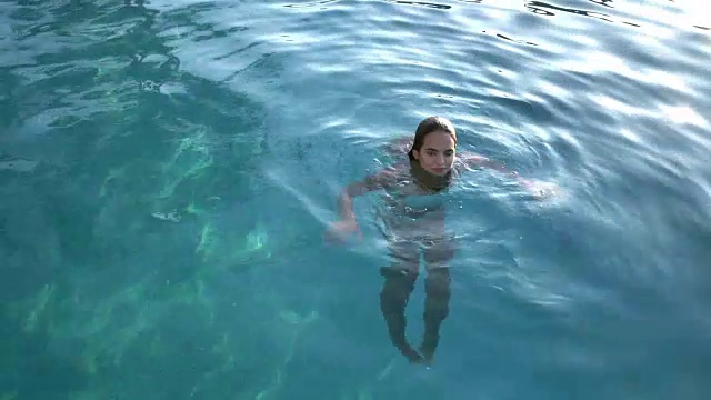 美丽的女人在游泳池里游泳视频素材