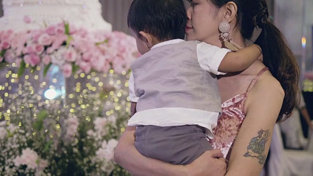 快乐的女人在婚礼上抱着她的儿子玩。视频素材