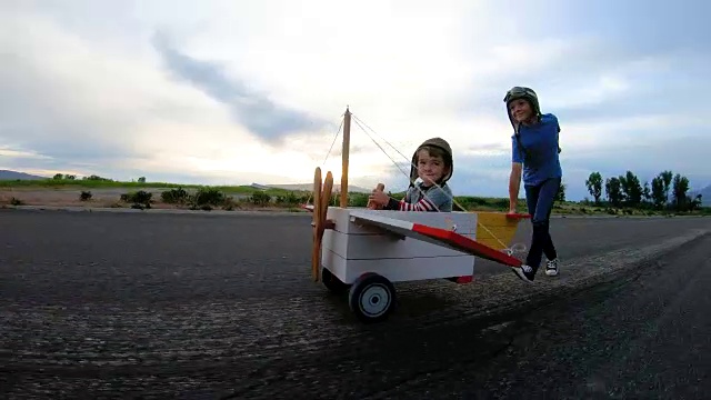 两个小男孩驾驶老式玩具飞机视频素材