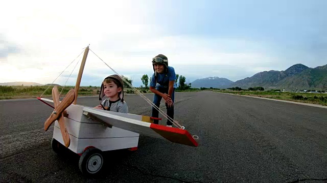 两个小男孩驾驶老式玩具飞机视频素材