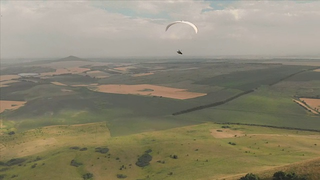 一个运动员骑着他的滑翔伞在燕子旁边飞行。无人机后续拍摄视频下载