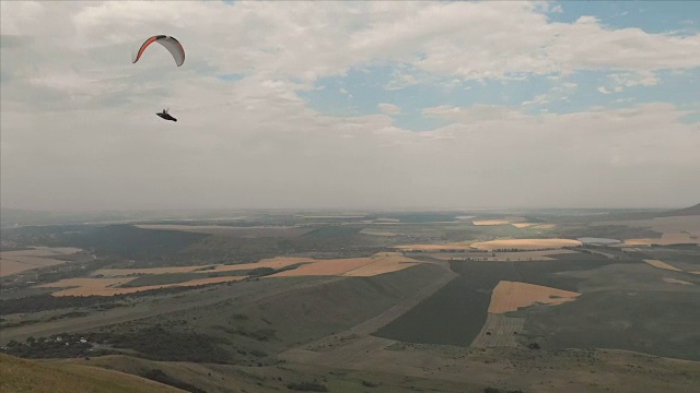 一个运动员骑着他的滑翔伞在燕子旁边飞行。无人机后续拍摄视频素材
