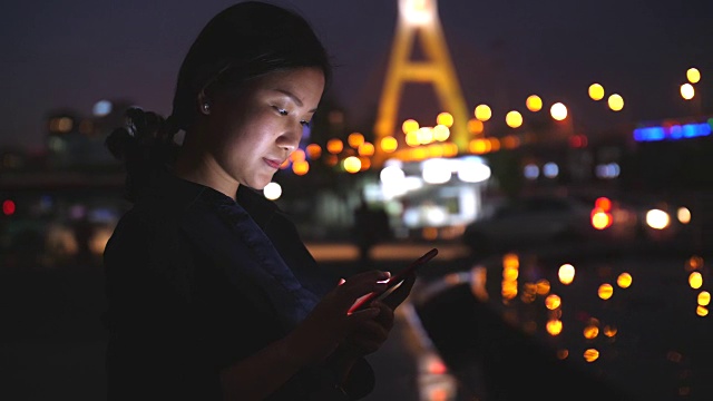 年轻的亚洲女性在晚上使用智能手机，4k视频素材