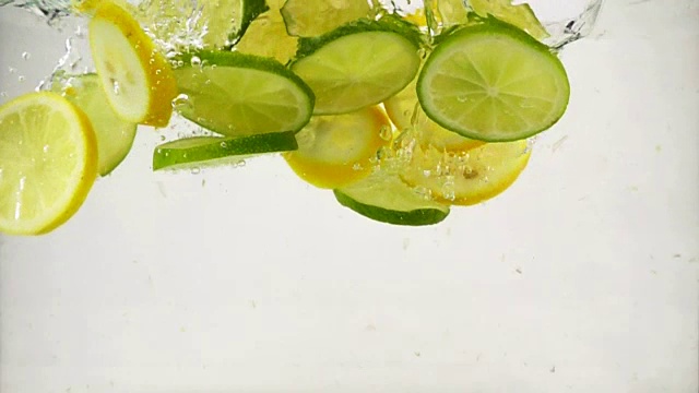 一片一片的酸橙和柠檬落入水中，溅起了水花和气泡，这是慢镜头特写视频素材