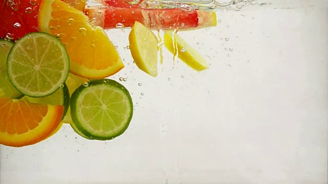 几片柠檬、柠檬、橙子、葡萄柚落入水中，溅起水花，冒出气泡，这是慢镜头特写视频素材