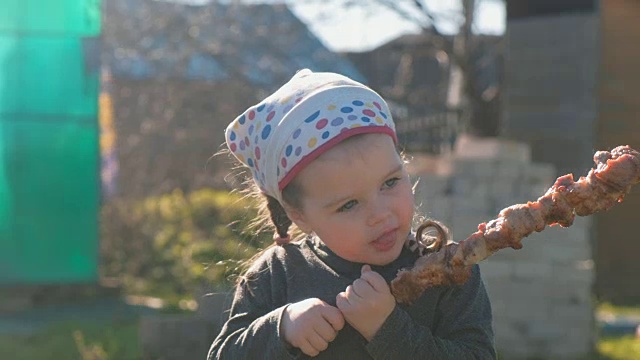可爱的小女孩吃烤肉串。视频下载