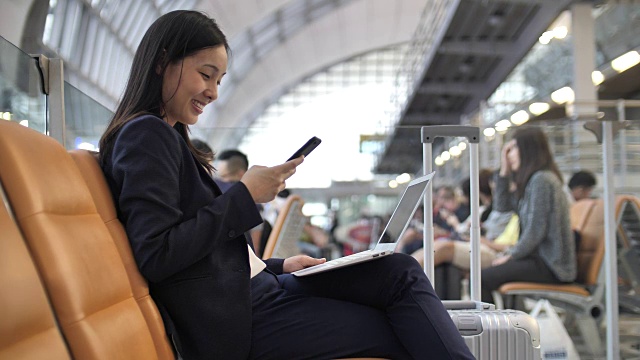 女商人在机场使用智能手机和笔记本电脑视频素材