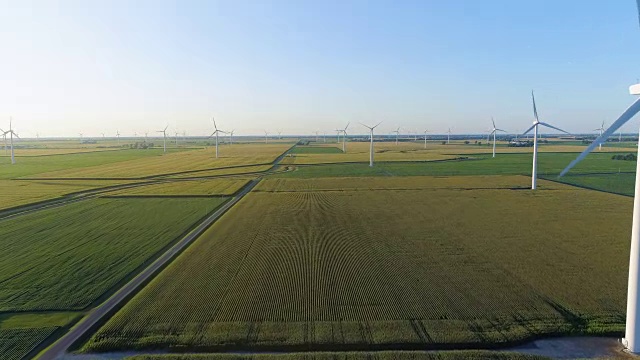低空飞行在乡村绿色的田野和白色的风力涡轮机在日落视频素材
