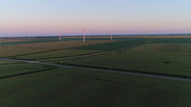 在夕阳下，用风力涡轮机在乡村绿地上空飞行视频素材