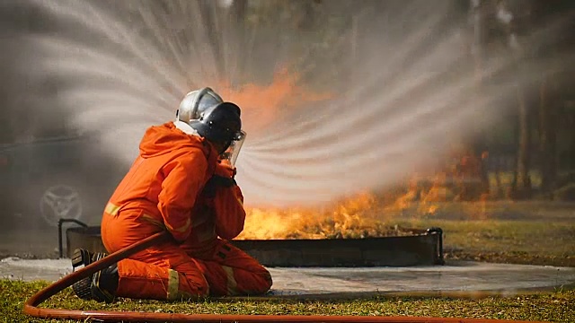 消防队员灭火行动，水通过高压喷嘴喷到火焰周围，烟雾缭绕，消防队员扑灭一辆汽车视频素材
