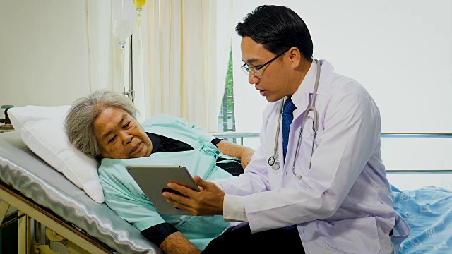 亚洲男医生使用数字平板电脑与资深病人在病房讨论视频下载
