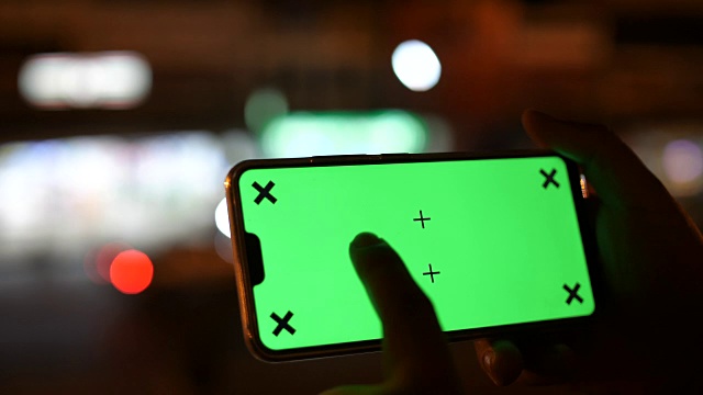 在景观模式下使用智能手机，绿色屏幕，夜间交通灯背景，色度键视频素材