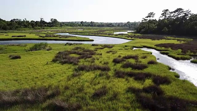 在北卡罗来纳州的翡翠岛，一架无人机在海岸内水道的沼泽草上空飞行视频下载