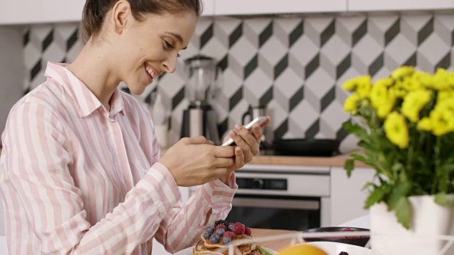 一个女人在厨房里拍摄煎饼和水果的早餐视频素材