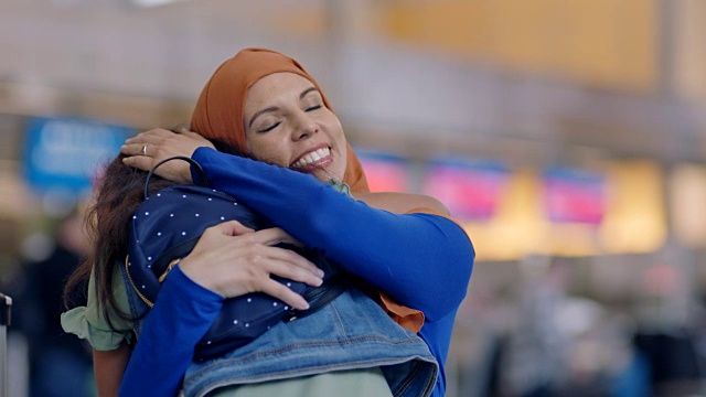 中东母亲和小女儿在机场航站楼奔向对方，拥抱在一起。视频下载