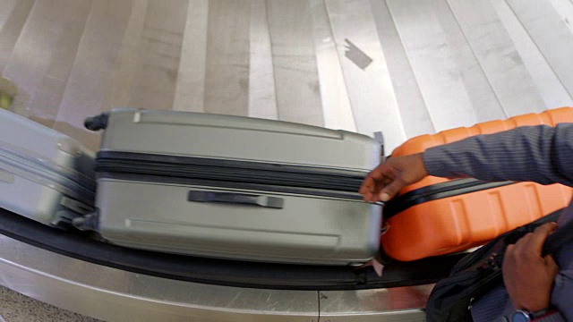 行李架上方，非洲裔美国商人在行李认领处从传送带上抢包。视频下载