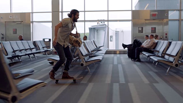 一个年轻人滑着滑板快速地通过机场候机区。视频素材