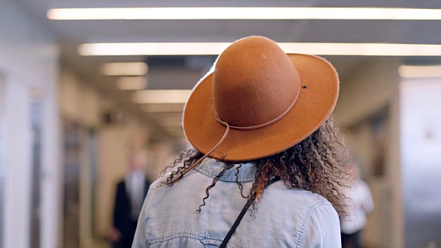 时尚年轻女子戴着帽子走过机场候机楼的移动肖像。视频素材