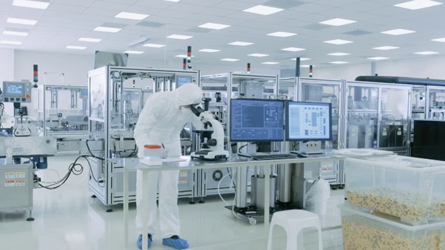 在无菌高精密制造实验室里，科学家们穿着防护服使用计算机和显微镜，做制药、生物技术和半导体研究。视频素材