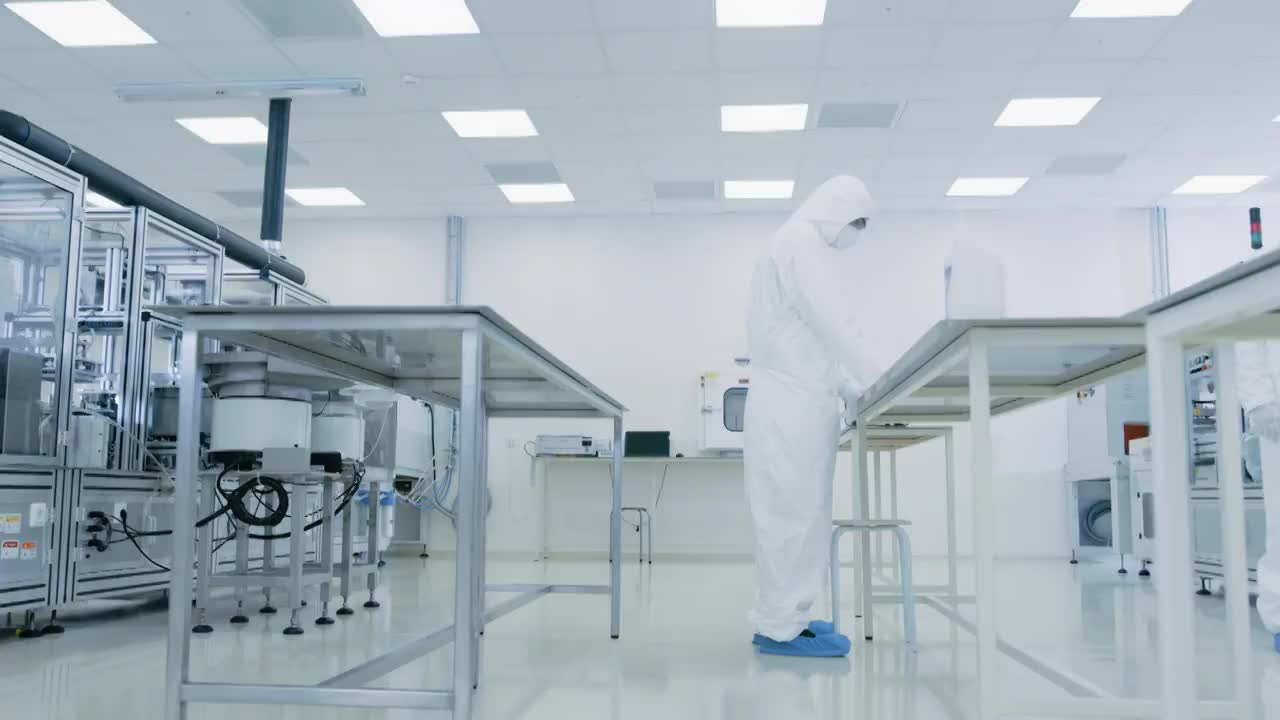 一队研究科学家在无菌服与计算机，显微镜和现代工业机械在实验室工作。产品制造工艺:制药，半导体，生物技术。视频素材