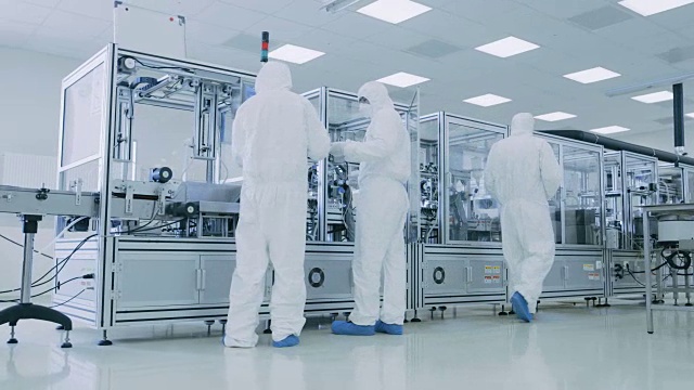 在穿戴无菌防护服的科学家制造工厂团队中，建立/编程现代工业3D打印机，高精度半导体加工。视频素材