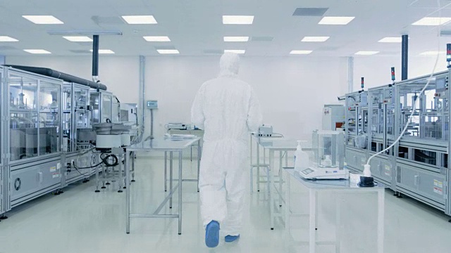 身着防护服的科学家带着成品箱通过实验室。工人在设施与现代工业机械。产品制造工艺:制药，半导体，生物技术。视频素材