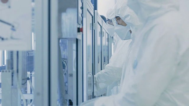 一组科学家穿着无菌防护服在现代工业3D打印机器上工作。制药、生物技术和半导体制造工艺。视频素材