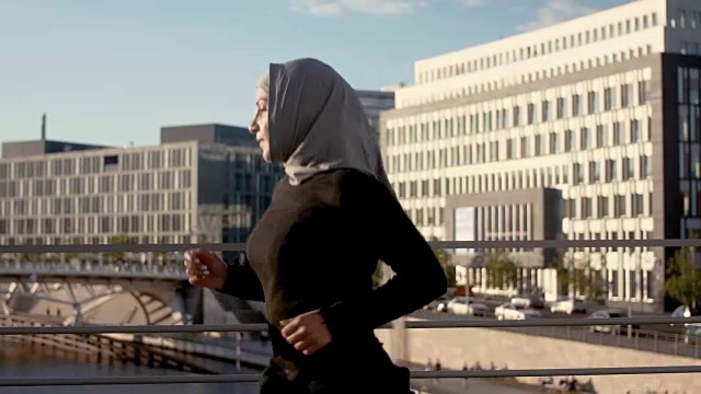 柏林中心的穆斯林妇女戴着头巾跑步的侧面图视频下载