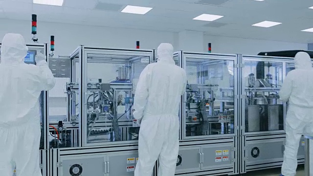 在无菌防护服制造设备的科学家团队在现代工业3D打印机械上工作。制药，生物技术和半导体创造/制造过程从内部拍摄。视频素材
