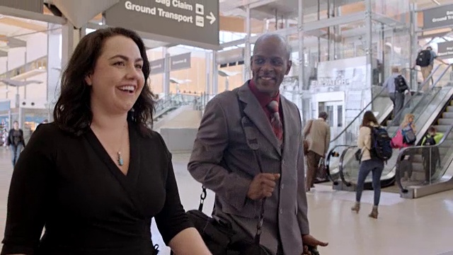 微笑的商人和女人穿过机场航站楼走向登机口。锅。视频素材