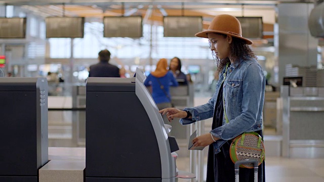 时髦的年轻女性旅客使用自助值机登记，扫描护照。视频素材