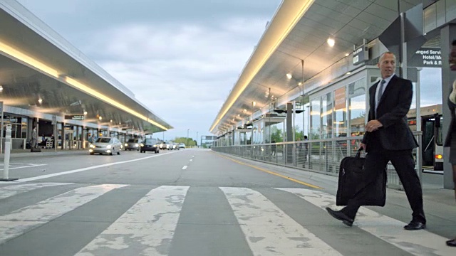 微笑着走过人行横道走向机场航站楼。视频素材