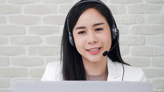 美丽的亚洲女接线员戴着麦克风在呼叫中心与客户交谈视频素材