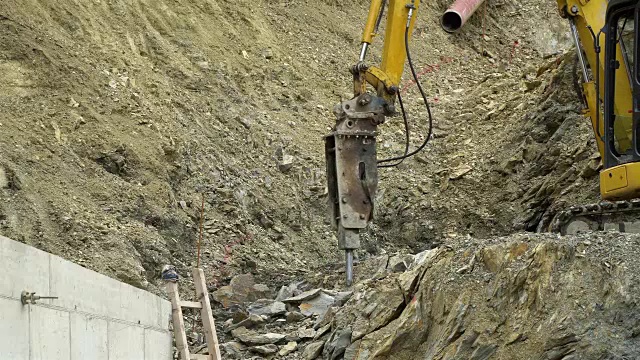 在建筑工地的采石场里，挖掘机上的大风动锤敲击岩石。视频素材