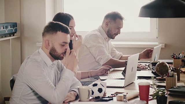 快乐的年轻欧洲商人坐在桌边，在现代健康的办公室里与笔记本电脑一起工作，慢镜头视频素材
