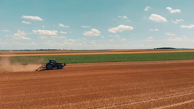 无人机拍摄的红色拖拉机在麦田里工作。欧盟农业与环境。视频素材