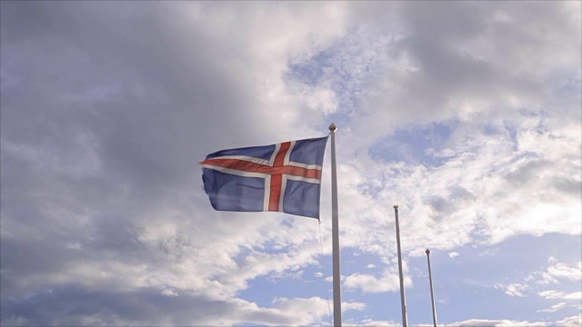 在日落时，冰岛国旗在天空和太阳下飘扬-慢动作视频-旅游目的地北欧国家的概念视频下载
