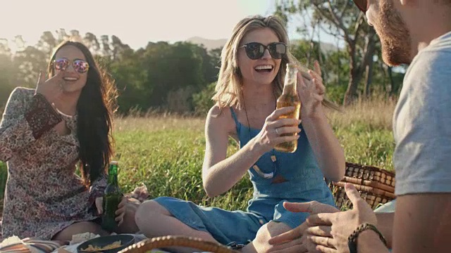 野餐时给朋友们递啤酒的快乐女人视频素材