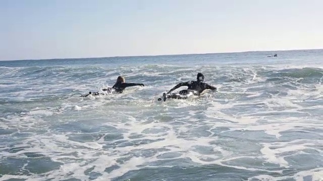 一对夫妇在冲浪板上划桨迎浪视频下载