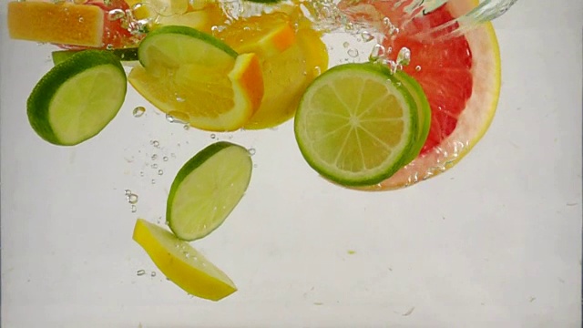 几片柠檬、柠檬、橙子、葡萄柚等柑橘类水果落入水中，溅起水花和气泡，这是慢镜头特写视频素材