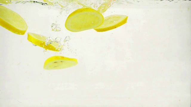 圆形柠檬片慢慢浸入水中，慢镜头特写视频素材