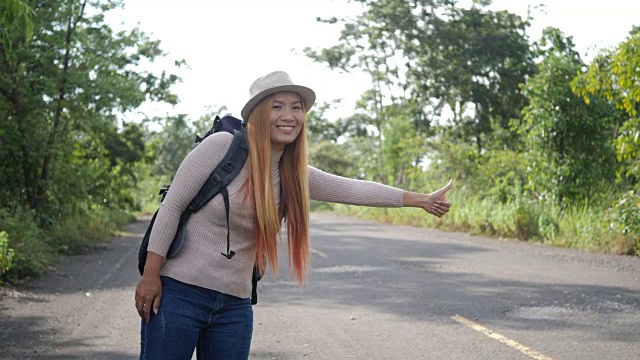 旅行者女子背包客搭便车在路上和行走。视频素材